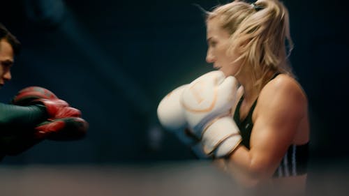 A Female Boxer Practising with her Trainer